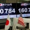 Two large screens show the USD/JPY exchange rate with US and Japan flags, foregrounded by desk flags (US and Japan).