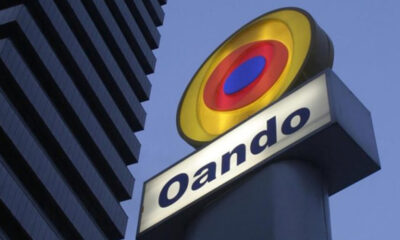 Oando company sign with a circular yellow-red-blue logo against a blue sky