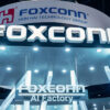 Foxconn booth signage at a tech expo with a large 'FOXCONN' logo and nearby 'AI Factory' text under bright lighting.