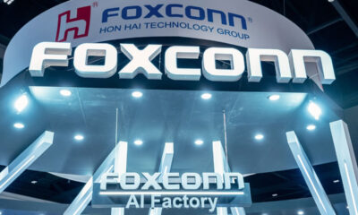Foxconn booth signage at a tech expo with a large 'FOXCONN' logo and nearby 'AI Factory' text under bright lighting.
