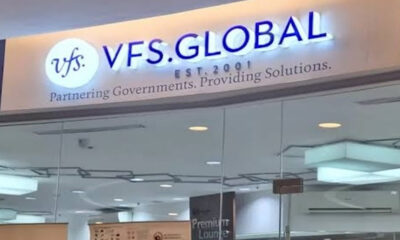 Sign reads 'VFS Global' with logo and the slogan 'Partnering Governments. Providing Solutions.' inside a modern office lobby.