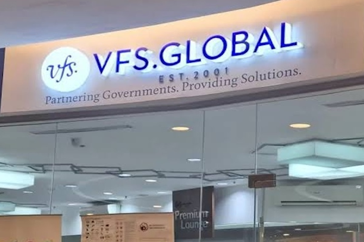 Sign reads 'VFS Global' with logo and the slogan 'Partnering Governments. Providing Solutions.' inside a modern office lobby.