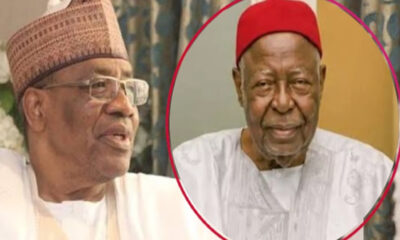 Two elderly men in traditional West African attire; left man wears glasses and a patterned cap, right man in a red fez-style hat inside a pink circle