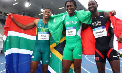 Three male sprinters on a track celebrate with national flags draped over their shoulders (South Africa, Nigeria, Trinidad & Tobago).