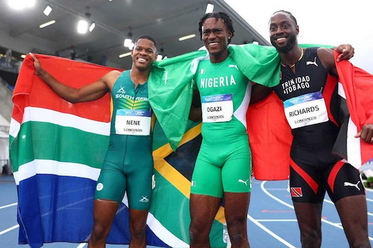 Three male sprinters on a track celebrate with national flags draped over their shoulders (South Africa, Nigeria, Trinidad & Tobago).